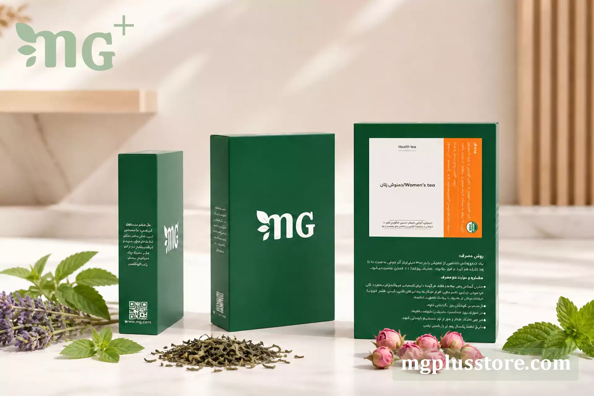 سه جعبه سبز رنگ دمنوش زنان ام جی پلاس در نماهای مختلف که همراه با غنچه‌های گل محمدی و برگ‌های تازه گیاهان روی یک سطح روشن و لوکس قرار گرفته‌اند.